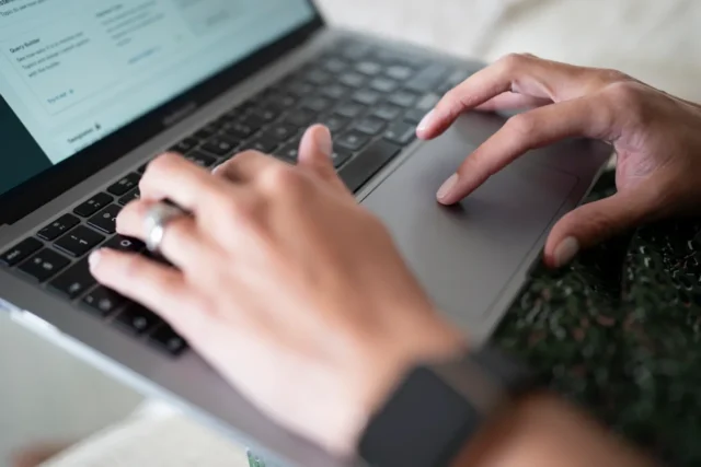 Close up of a womans hands working on a laptop